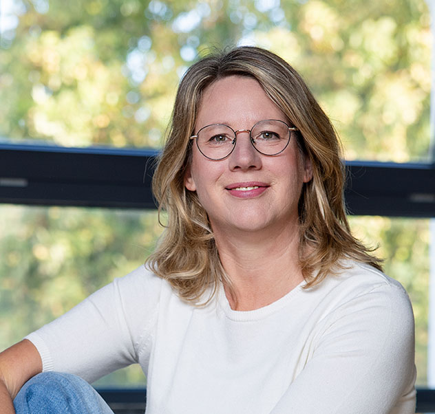 Stefanie-Kappus-Heilpraktikerin-für-Psychotherapie in Urbar. Stefanie sitzt vor einem Fenster, weißes T-Shirt und Jeanshose.